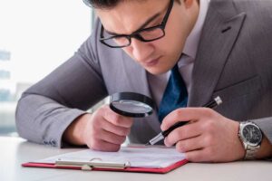 uomo controlla documenti con lente ingrandimento
