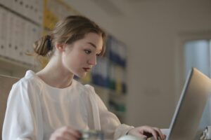 Ragazza con camicetta bianca che lavora al laptop