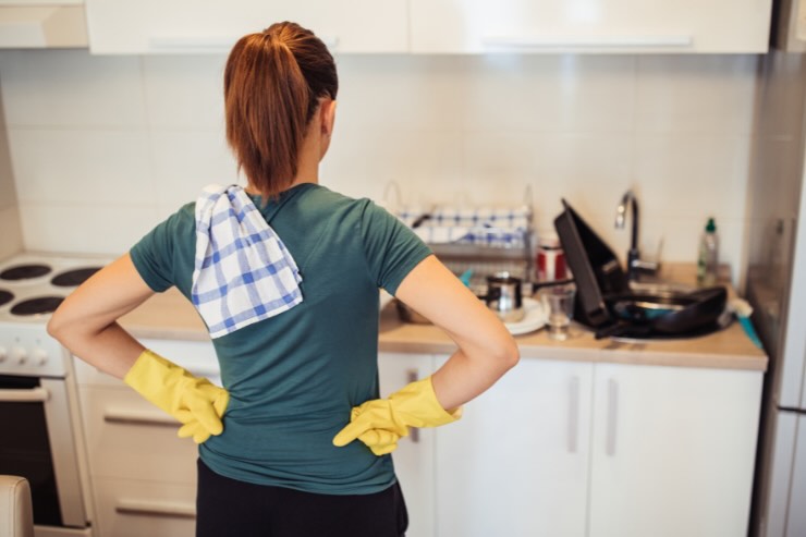 donna di spalle con i guanti gialli e canovaccio sulle spalle