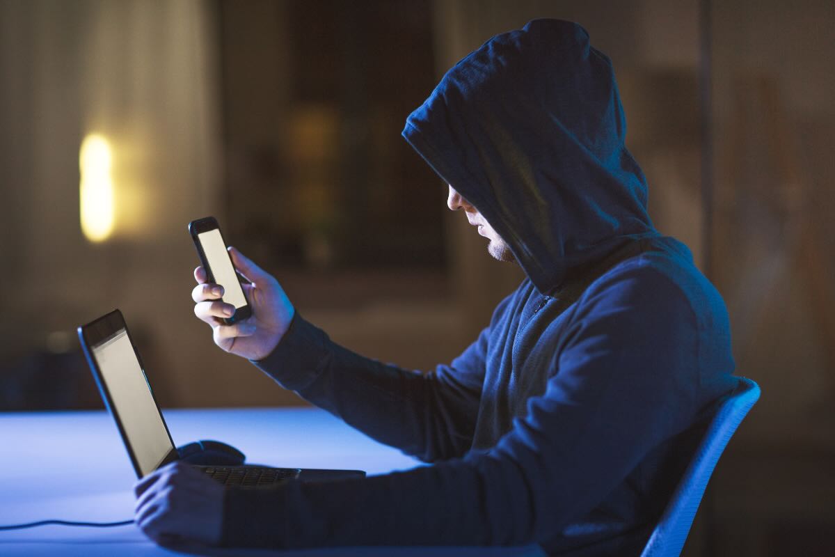hacker con tablet e smartphone in mano 