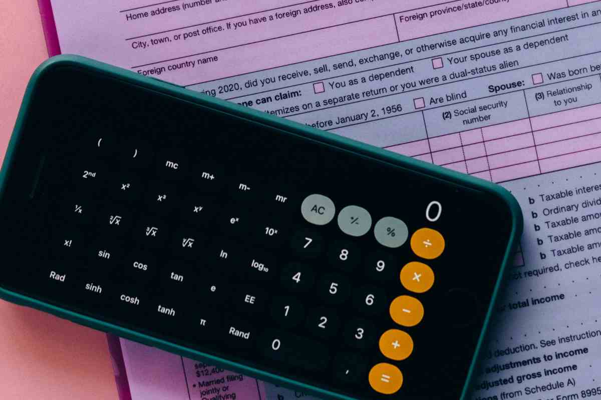 Una calcolatrice sullo smartphone e, sotto, un documento fiscale
