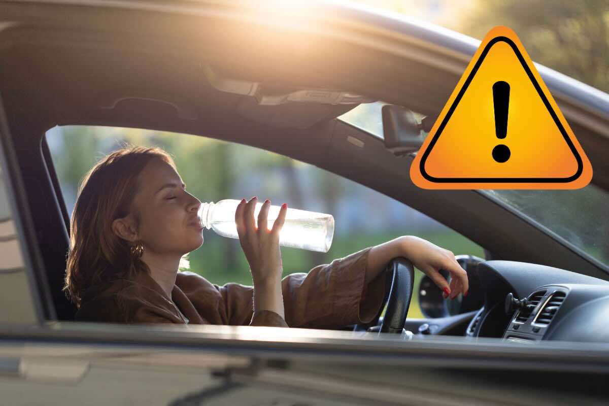 donna che beve acqua in auto e segnale pericolo