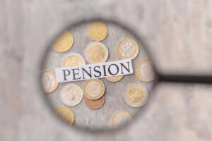 Lente di ingrandimento inquadra scritta "pension" e monete