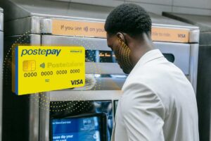 Un uomo che preleva contante a un ATM e, in evidenza, una Postepay