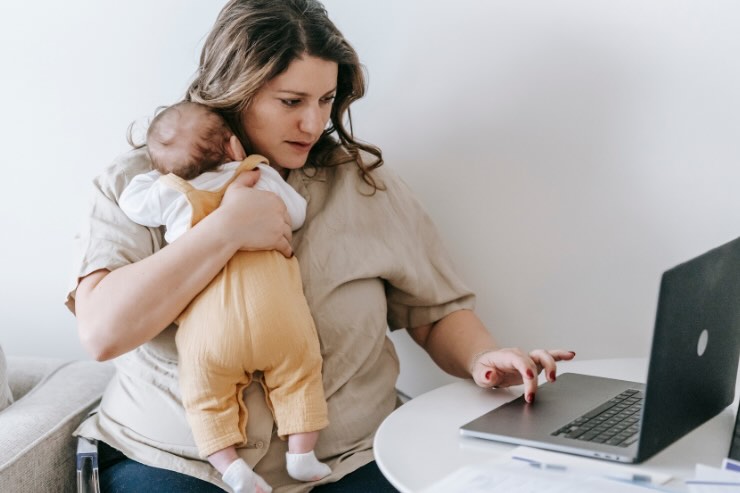 donna che lavora al pc con neonato in braccio