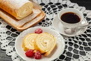 Fette di rotolo dolce con lamponi, tazza di caffè