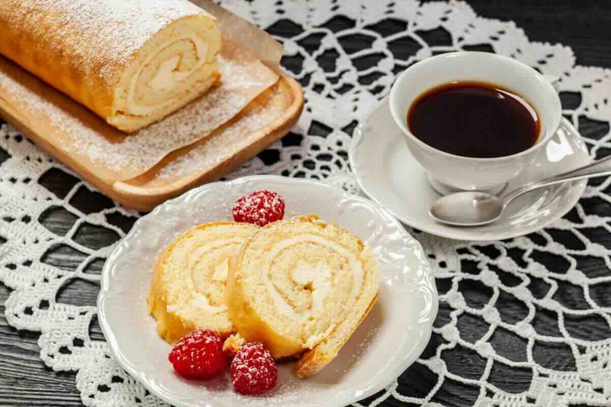 Fette di rotolo dolce con lamponi, tazza di caffè
